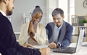 Woman watches as her husband signs a contract to rent or buy property in the office.