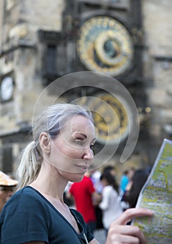 Woman watches the map of the city on background of historical medieval astronomical Clock on the Old Town Hall in Prague, Czech Re