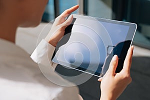 A woman watches media content, showing a blank screen of a tablet. The concept of a video conference during online work