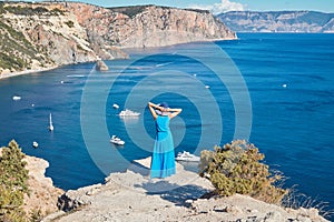 Woman watching beautiful coastline. Yachts floating on sea and magnificent mountains. Travelling and vacation concept