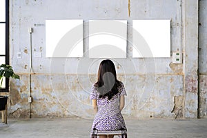 Woman watching blank photo frame on white wall art gallery