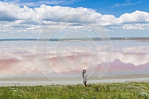 Woman watching at clouds reflection in pink lake surface. Beautiful spring