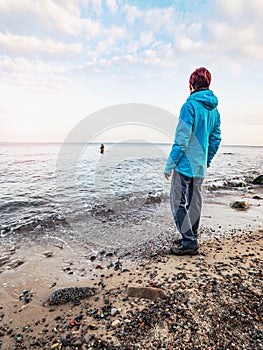 Woman is watching fishing man wading in the cold water. Man fishing