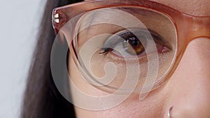 Woman watching or gazing with trendy optometry vision glasses. Closeup of eyes looking forward while wearing optician