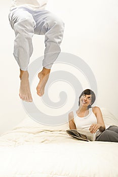Woman watching husband jump on bed