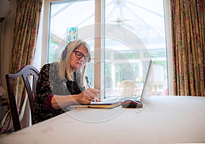 Woman watching live webinar on her laptop,wearing headphones photo