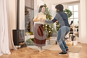 Woman watching man dancing near x-mas tree indoors