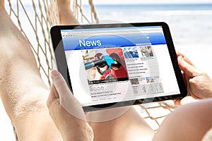 Woman Watching News On Digital Tablet At Beach