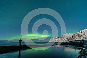 Woman watching the northern lights, Aurora Borealis, Devil Teeth mountains in the background, Tungeneset, Senja, Norway