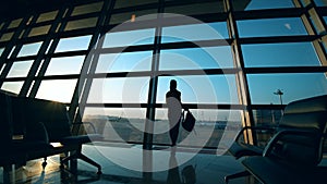 A woman is watching the planes from the departure lounge