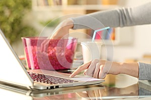 Woman watching streaming tv on laptop with popcorn