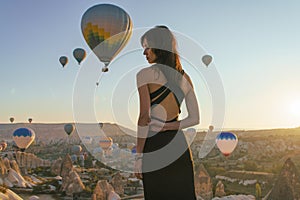Woman watching the sunrise and hot air balloons