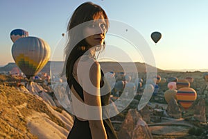 Woman watching the sunrise and hot air balloons