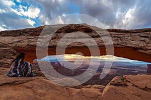 Woman watching the sunrise at Mesa Arch, Canyonlands National Park, Utah, USA