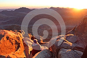 A woman watching the sunrise on the top of mountain Moses in Saint Catherine in Sinai