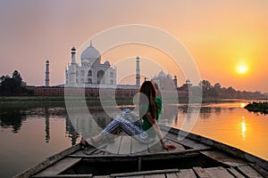 Woman watching sunset over Taj Mahal from a boat, Agra, India