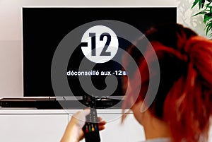 Woman watching television that display french disclaimer message