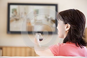 Woman watching television using remote control