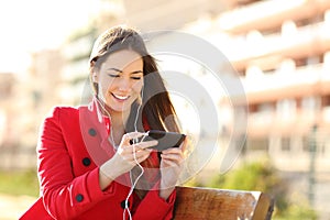 Woman watching videos in a smart phone with earphones photo