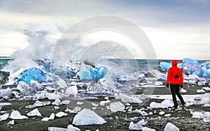 Woman watching waves crash against icebergs at Jokulsarlon glacial lagoon near Vatnajokull National Park, southeast Iceland photo