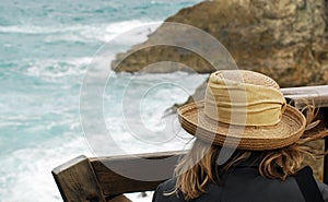 A Woman Watching Waves Crash over rocks on Beach