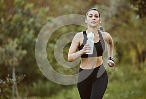 Woman, water bottle and running in nature for fitness, workout or outdoor exercise with hydration. Active person