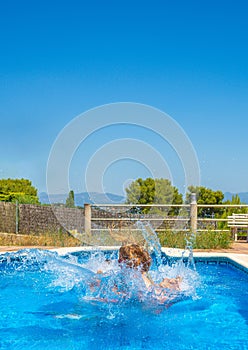 A woman in the water after jumping from the edge of a pool and with her head out of the water in the middle of strong waves with