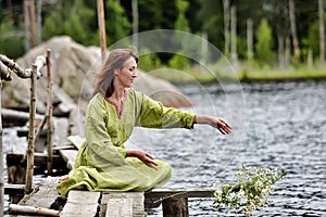 Woman by the water with a wreath in her hands