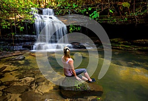 Woman at waterfall and swimming hole in bushland wilderness