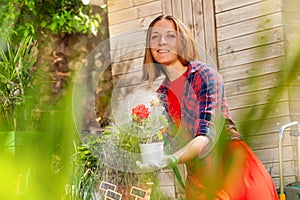 Woman watering garden flowers with hose sprinkler