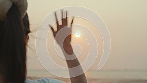 Woman waving hand say goodbye or parting with sunset alone on the seaside