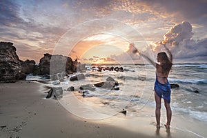 Woman waving at the sun near the sea