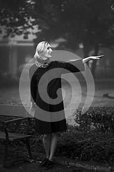 A woman waving to acquaintances standing on the street.