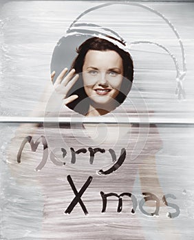 Woman waving at window with Christmas greeting