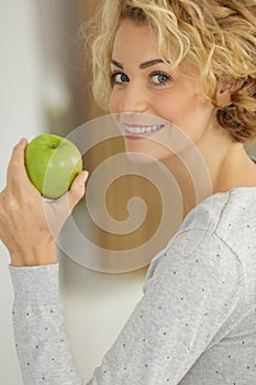 woman with wavy hair posing with apple at home