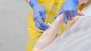 Woman waxing arm in sportswear outfit with blue gloves