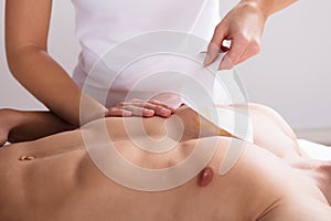 Woman Waxing Man`s Chest With Wax Strip photo