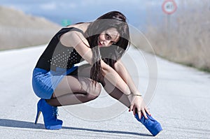 Woman wear a blue skirt and black stockings pose on the open road