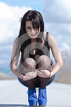 Woman wear a blue skirt and black stockings pose on the open road