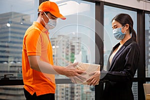 Woman wear face mask receiving parcel from delivery service, Young delivery man employee in t-shirt uniform wear face mask