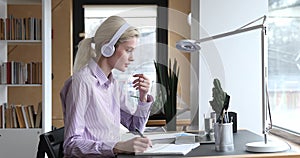 Woman wear headphones talk with tutor by notebook and videoconference