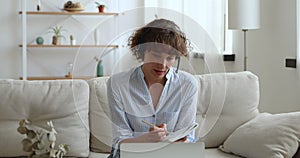 Woman wear headset writing notes during videocall with online tutor