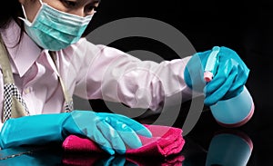 Woman wear a hygienic mask , use blue rubber glove holding pink microfiber cleaning cloth and spray bottle with sterilizing photo