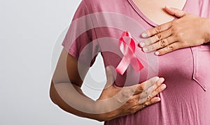 Woman wear pink t-shirt she have pink breast cancer awareness ribbon on chest she hold breast by hand