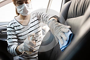 Woman wear protective glove,spraying alcohol antiseptic,disinfecting spray,cleaning on backrest,seat in car,protection during photo