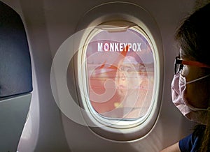 Woman wear surgical mask sit on passenger seat near cabin window of the airplane with monkeypox outbreak concept. Monkeypox is photo