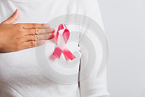 Woman wear white shirt she have pink breast cancer awareness ribbon and uses handles on chest