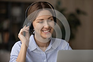 Woman wear wireless headset smile looks at laptop screen