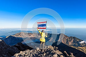 Woman wear yellow black jacket standing on top of Rinjani mountain and enjoy volcano, lake and clear blue sky after finish hiking