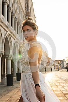 Woman wearing beautiful white dress walking on a street of the Venice city